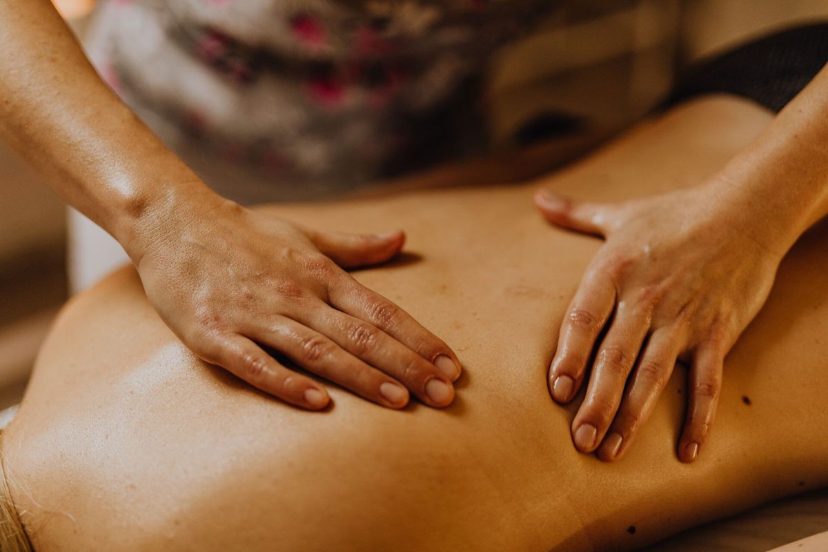 Zwei Hände gleiten mit Öl langsam über den Rücken bei einer Rückenmassage